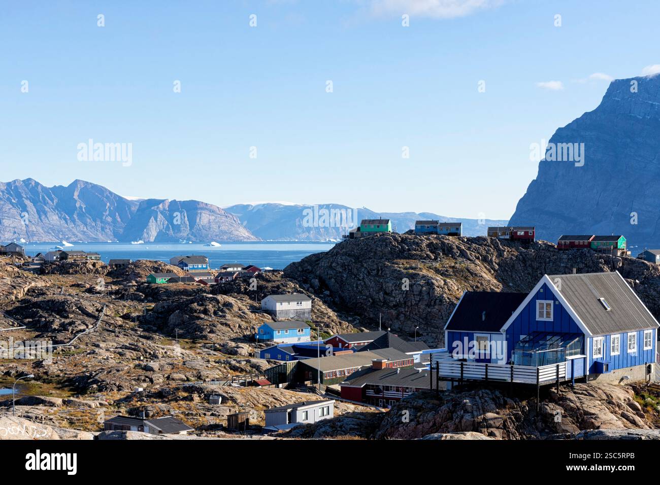 Case di Colourfullhouse costruite su rocce con vista sul fiordo di Uummannaq, gli iceberg e la costa opposta con le sue montagne. Uummannaq, Groenlandia, Danimarca Foto Stock