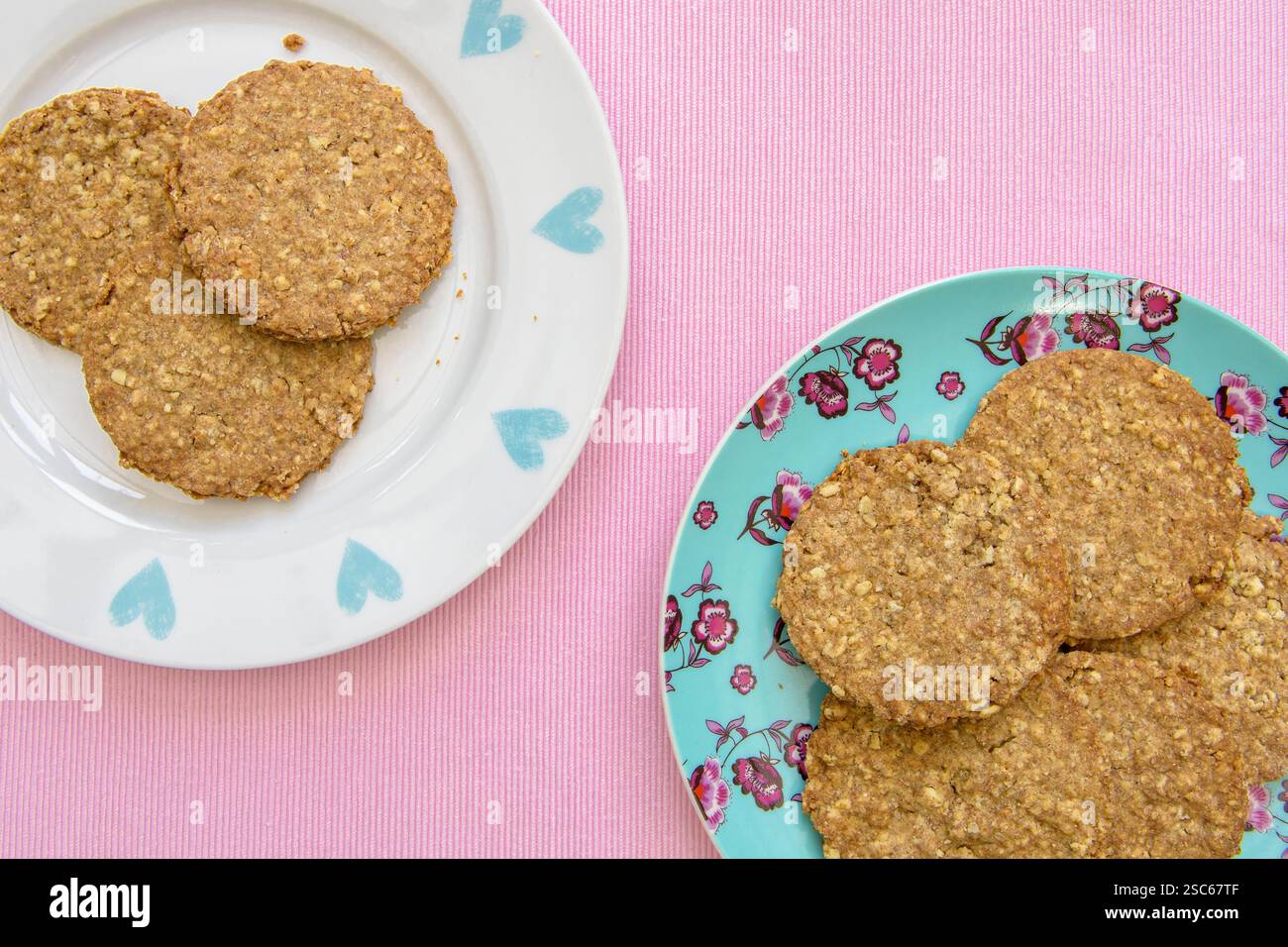 Biscotti digestivi appena sfornati su piatti deliziosi su sfondo rosa Foto Stock