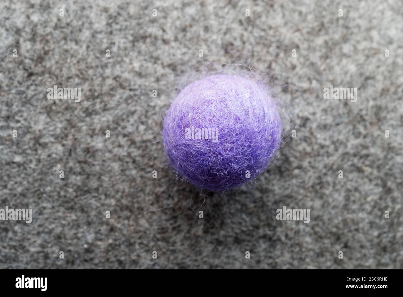 sfera rotonda in feltro viola con sfondo grigio in feltro Foto Stock