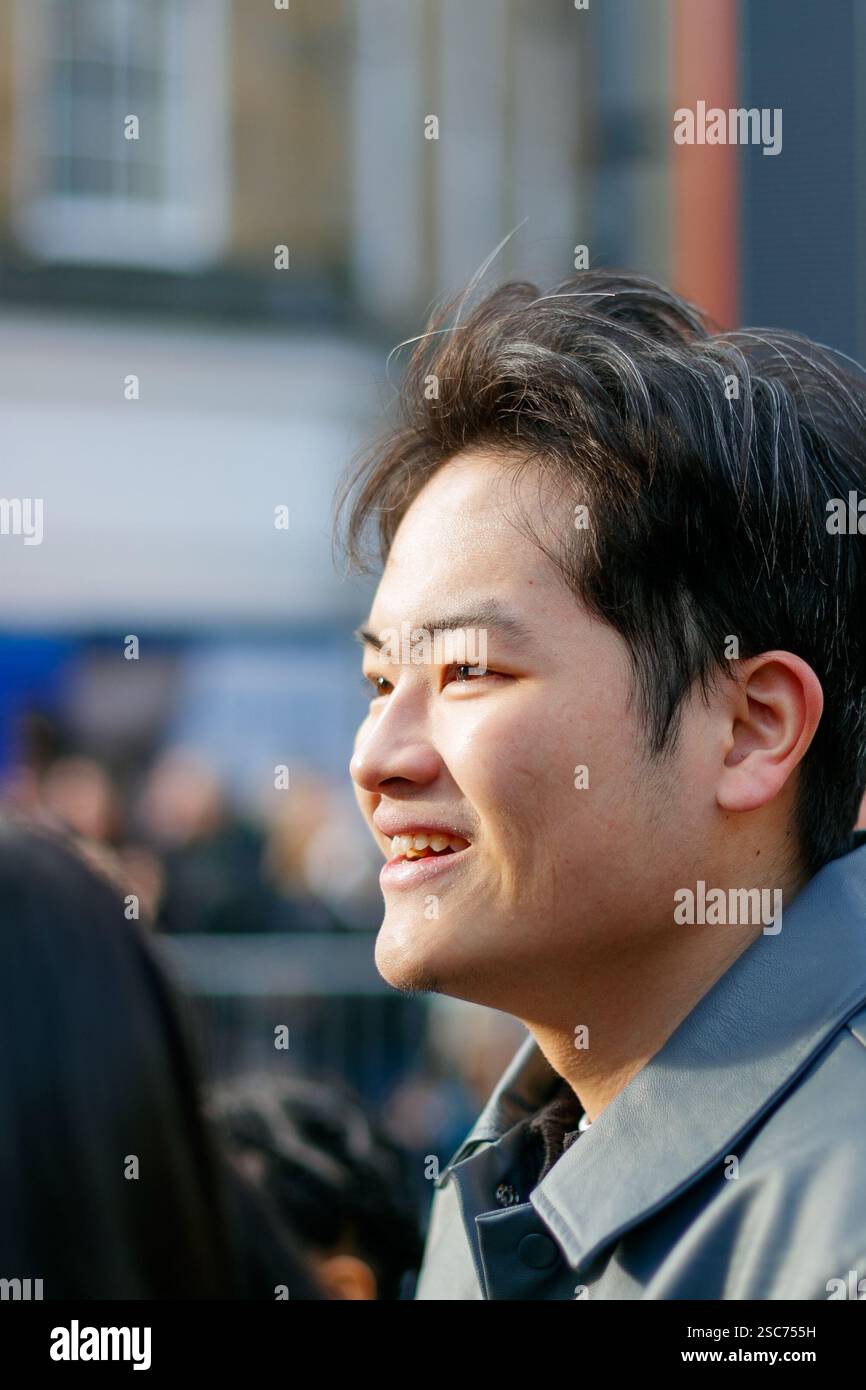Primo piano di un uomo asiatico sorridente con i capelli corti in un ambiente urbano all'aperto durante la parata cinese del capodanno newcastle upon tyne, regno unito Foto Stock