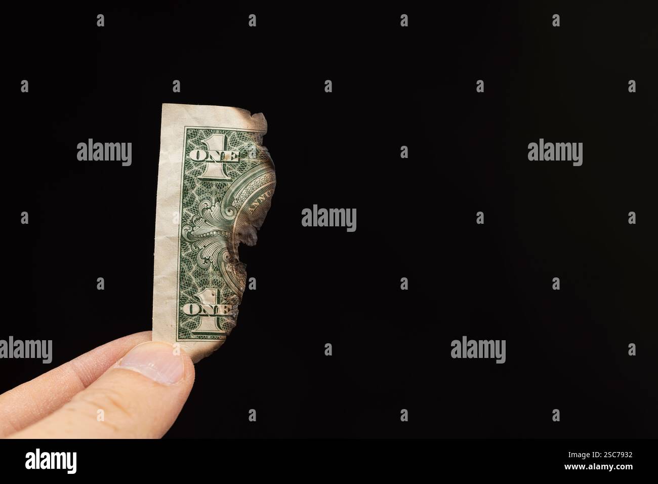 Dollari americani in mano danneggiati e parzialmente distrutti dal fuoco , una vecchia banconota di un dollaro americano danneggiata dal fuoco, su sfondo nero Foto Stock
