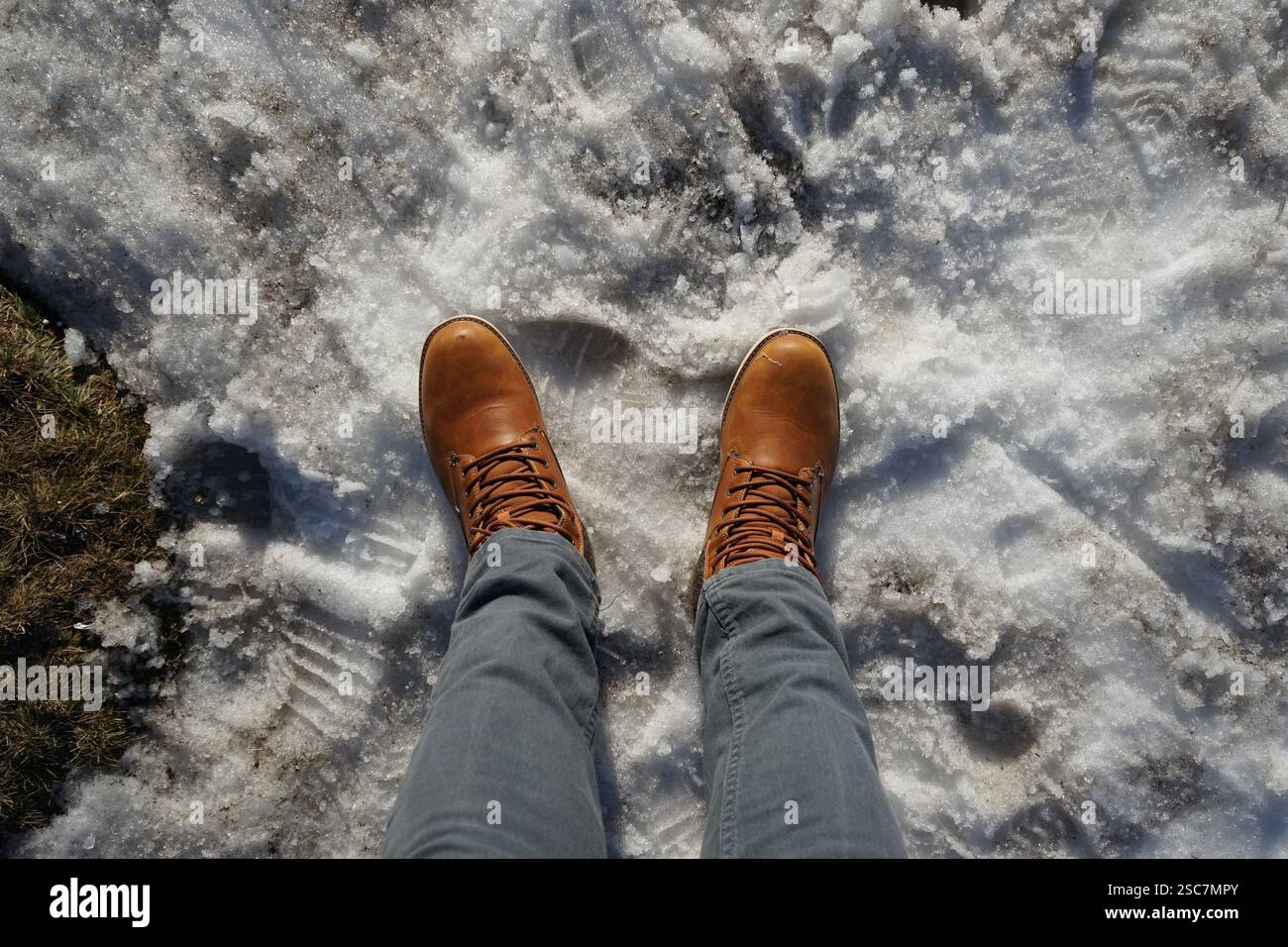 Tagliato di gambe con pantaloni grigi, scarpe marroni sulla neve Foto Stock