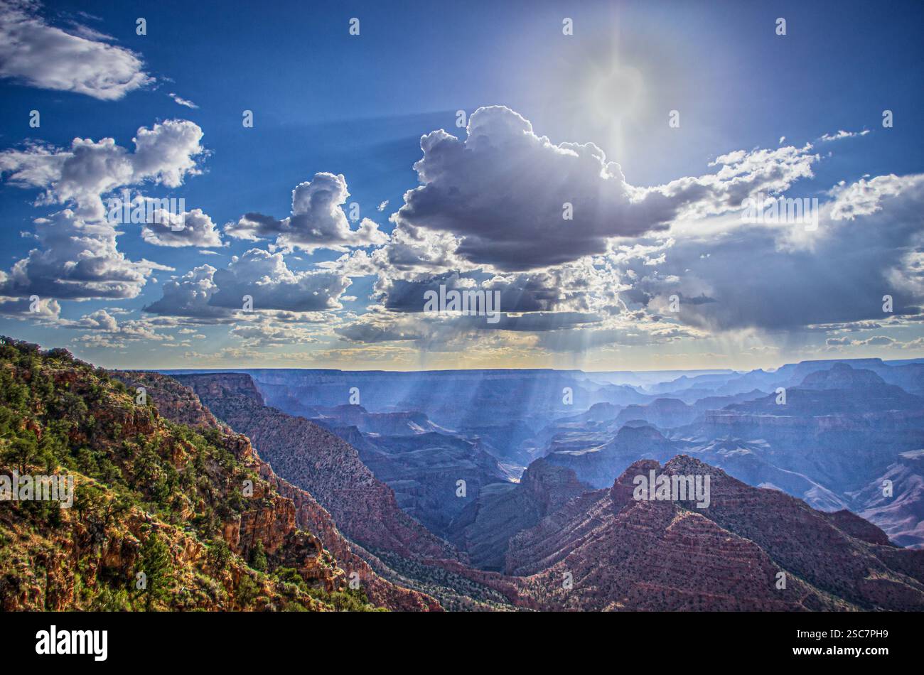 I raggi del sole si infrangono attraverso le nuvole sul Grand Canyon, evidenziando aspre scogliere e vasti paesaggi sotto un cielo spettacolare. Foto Stock