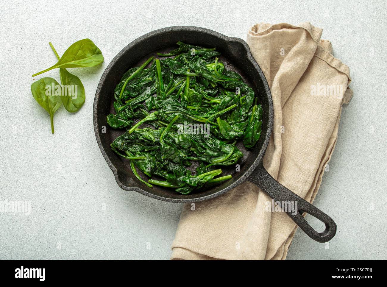 Spinaci cotti al vapore in una padella di ghisa Foto Stock