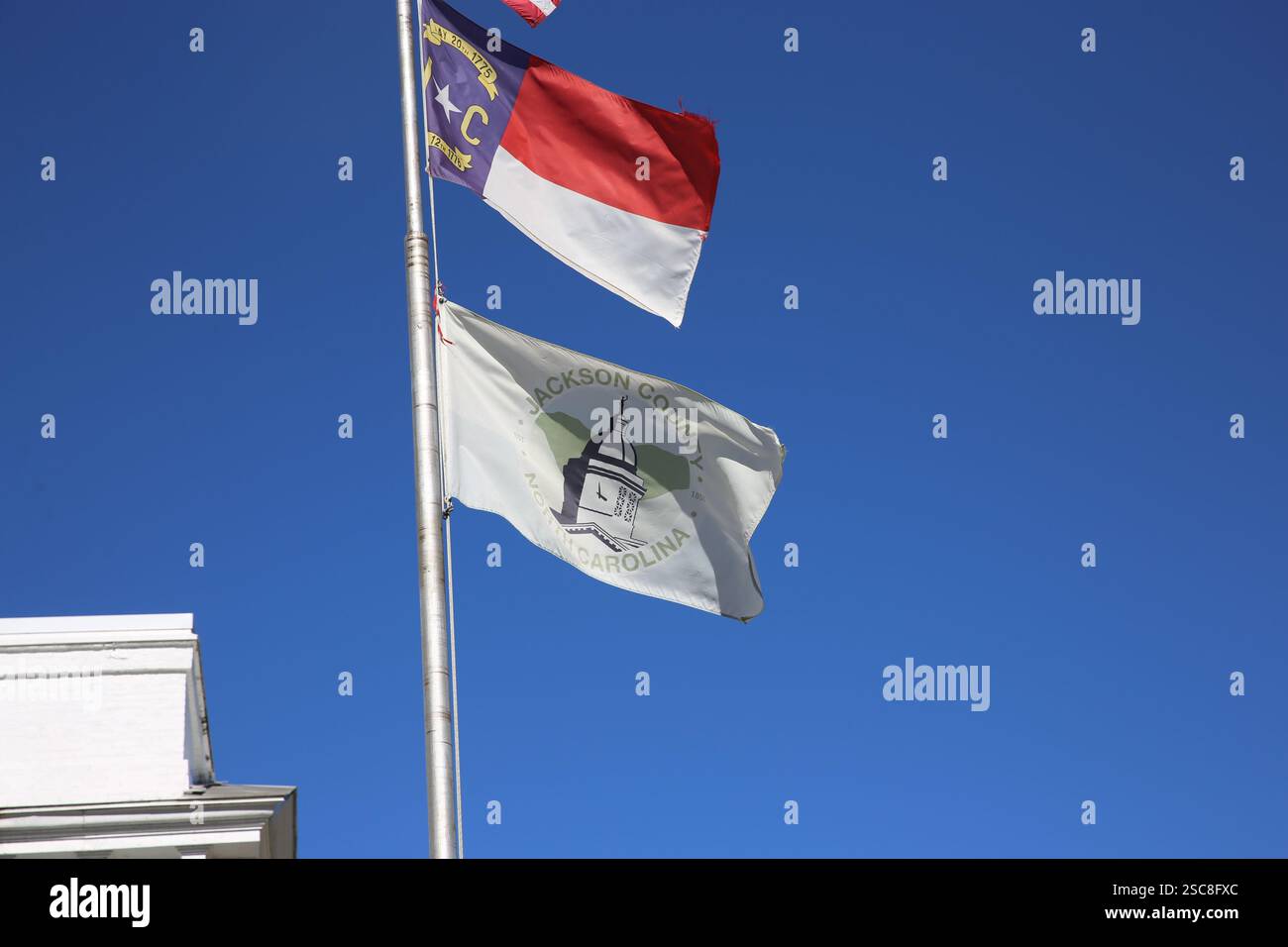 La bandiera della contea di Jackson e la bandiera dello stato della Carolina del Nord ondeggiano davanti allo storico tribunale in una giornata limpida nella città di Sylva, North Carolina. Foto Stock