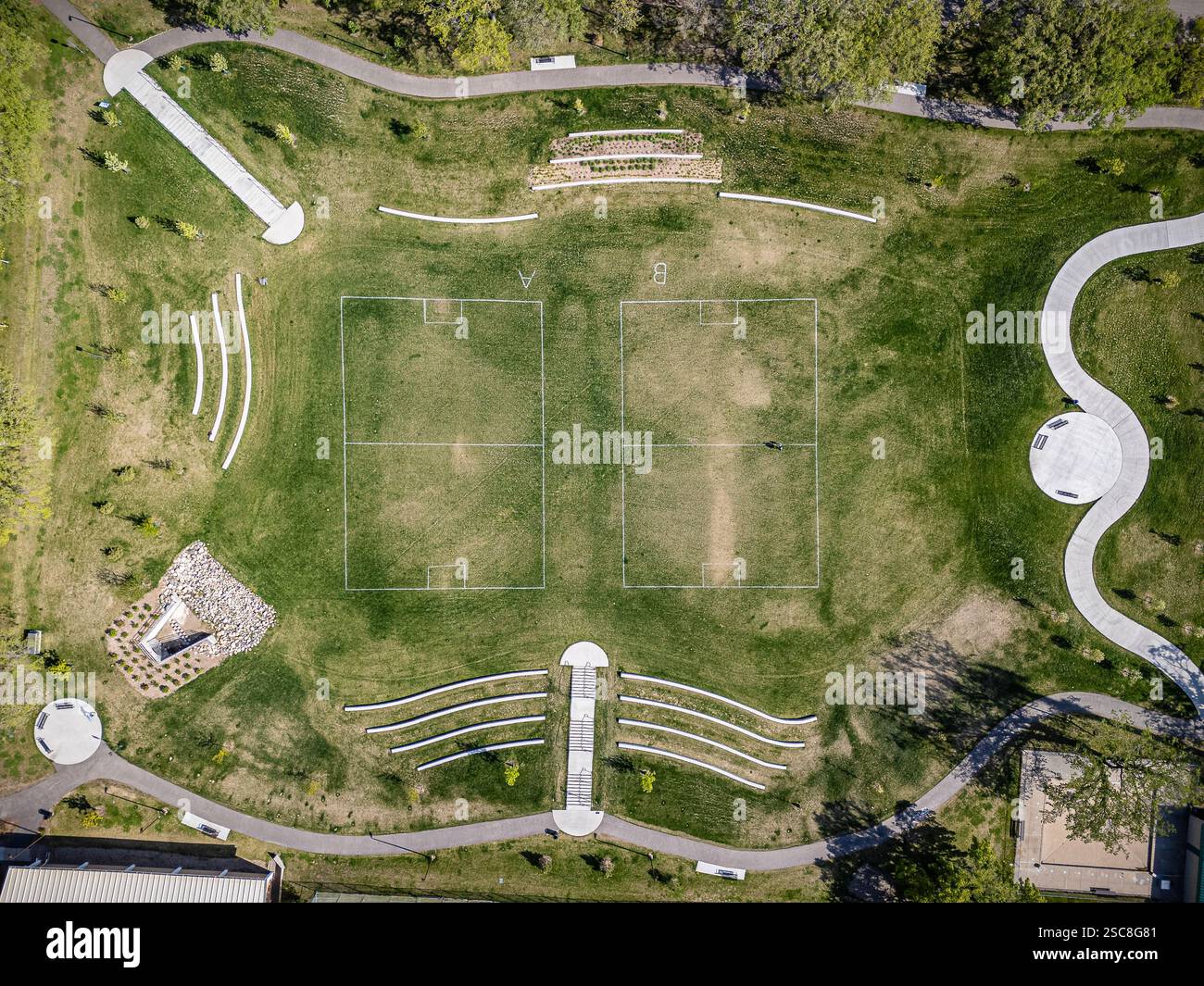 Parco con un grande campo erboso e alcune panchine. Le panchine sono disposte in un semicerchio intorno al campo Foto Stock