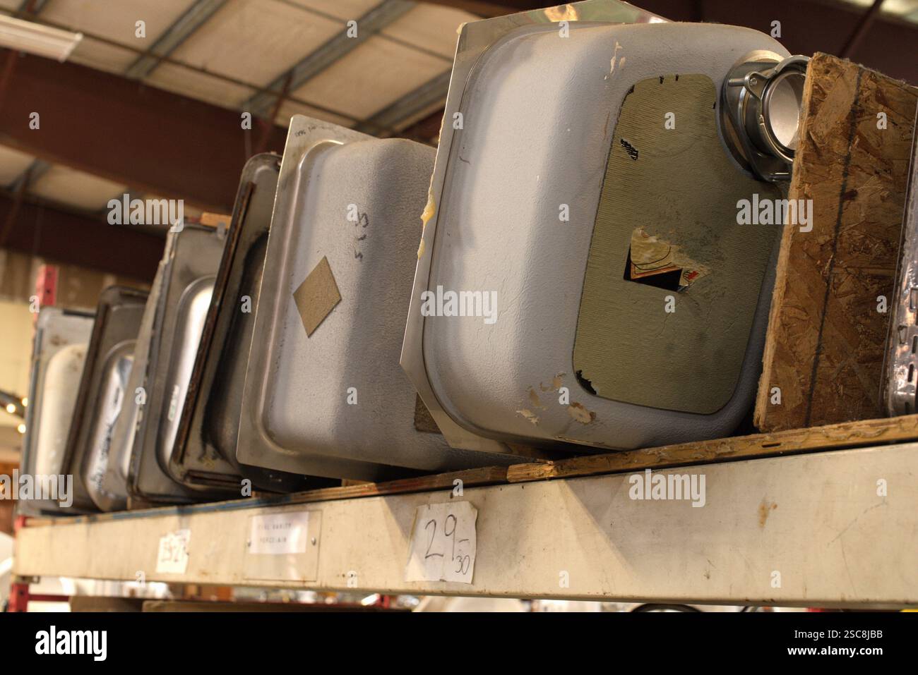 Vista verso l'alto di una fila di lavandini da cucina allineati su un ripiano di legno aperto all'interno di un magazzino. Foto Stock