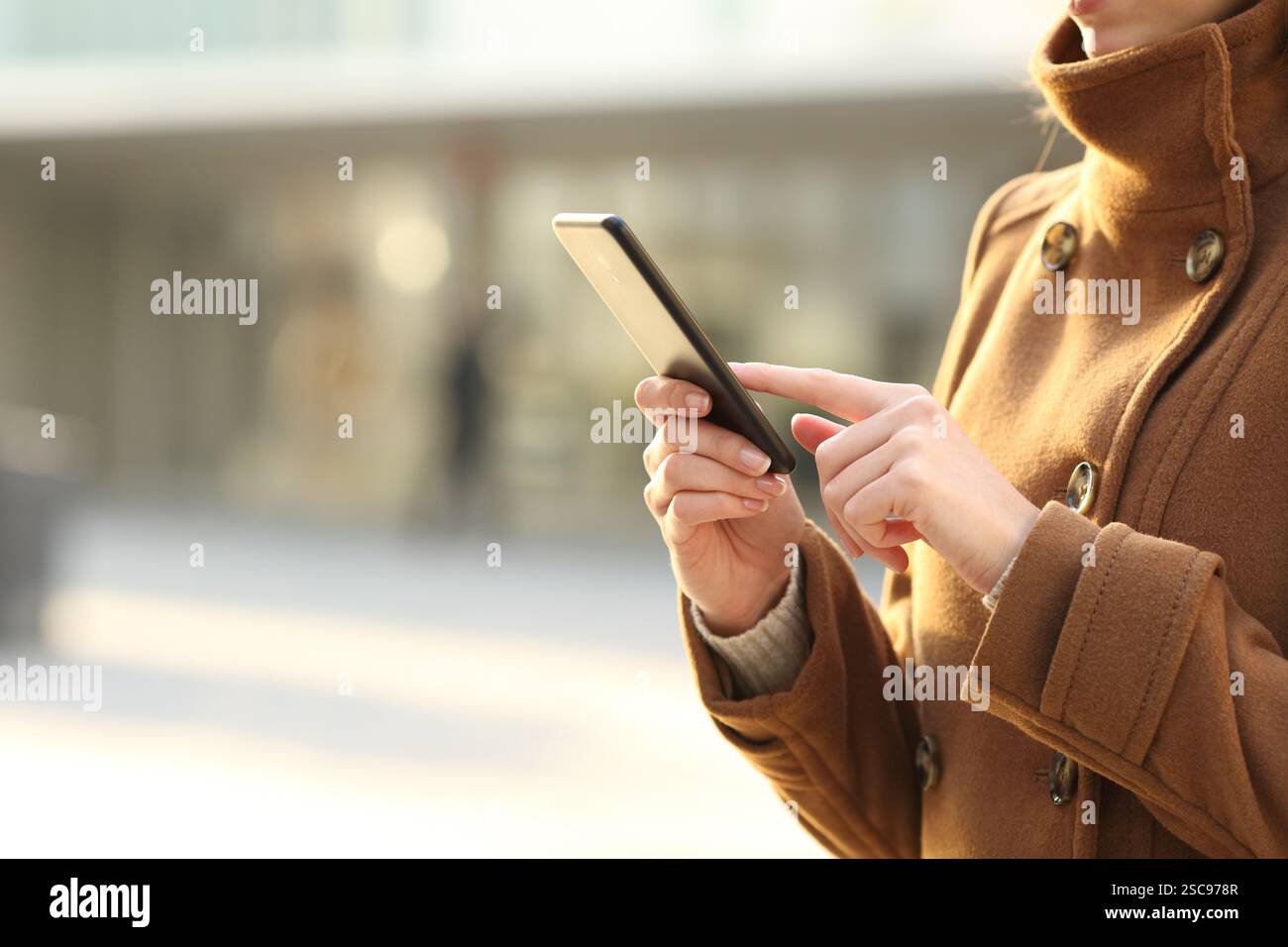 Primo piano di una donna che usa lo smartphone in inverno per strada Foto Stock