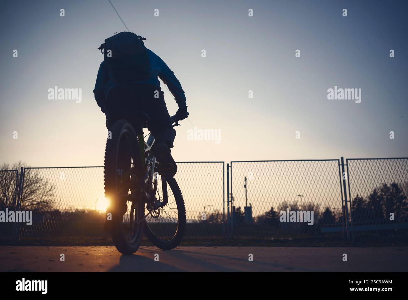 Un ragazzo cavalca una bicicletta estrema, pratica sull'asfalto al crepuscolo. Foto Stock