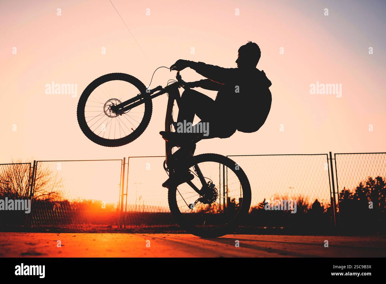 Un ragazzo cavalca una bicicletta estrema, pratica sull'asfalto al crepuscolo. Foto Stock