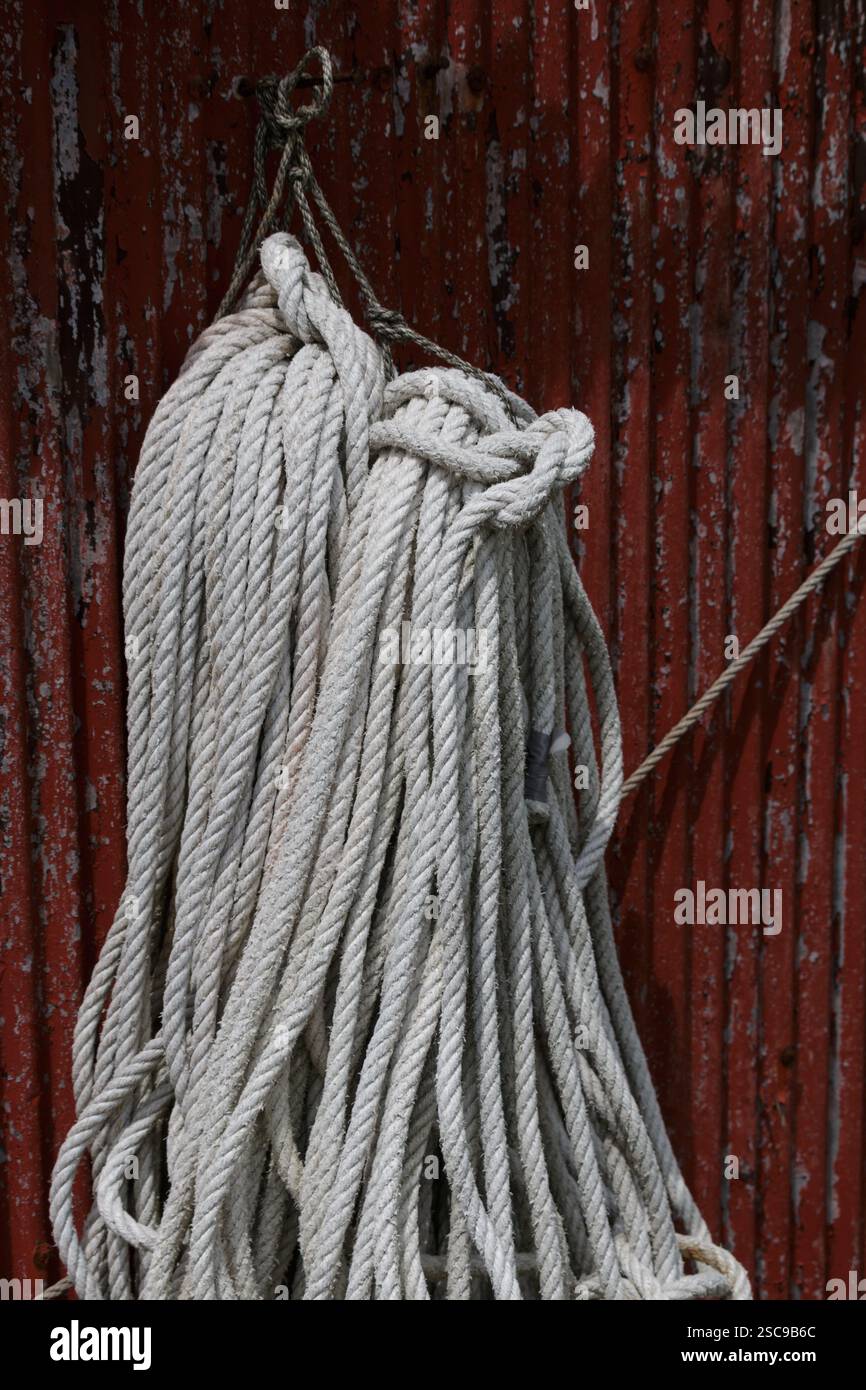 Fune bianca appesa su capannone in metallo ondulato rosso Foto Stock