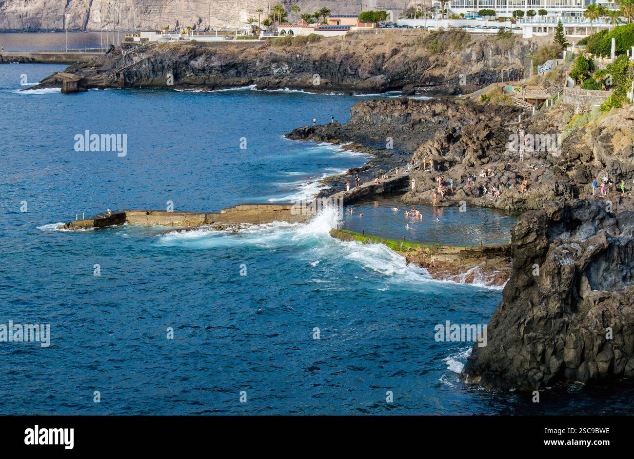 Los Gigantes, Santa Cruz de Tenerife, Spagna - 01FEB2025 - persone che nuotano e si divertono nella piscina di roccia lavica naturale chiamata Charco de Isla Cangrejo. Foto Stock