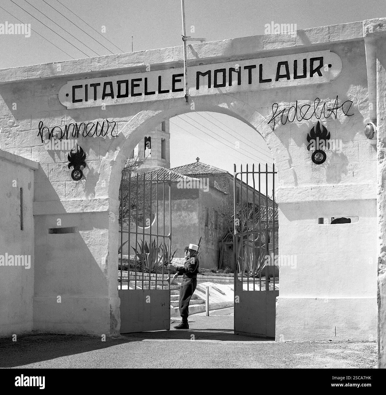 Il cancello d'ingresso di una caserma legionaria straniera dove un soldato uniforme sta chiudendo il cancello. [traduzione automatica] Foto Stock