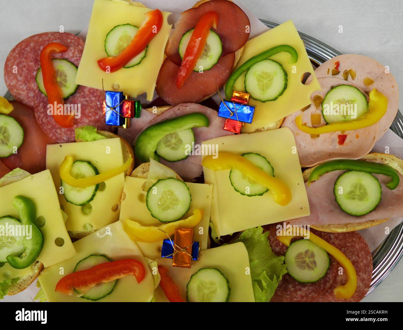 Panini con salsiccia e formaggio, guarniti con cetrioli e peperoni, uno spuntino salato popolare per eventi e feste, perfetto per qualsiasi buffet Foto Stock