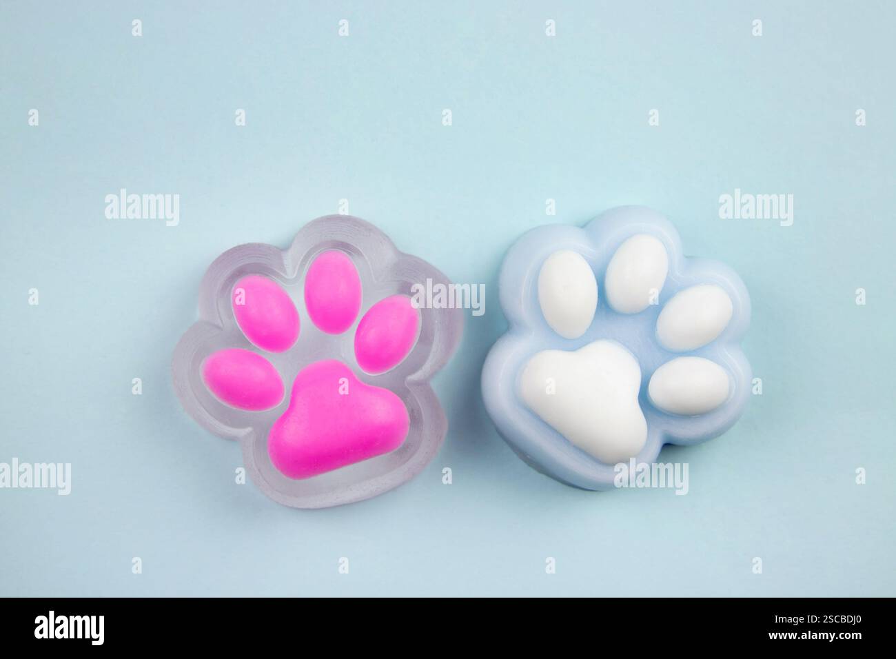 Simpatici e colorati giocattoli a forma di zampa di gatto squishy Jelly Slime su sfondo blu, foto in studio, copia spazio. Moderno e popolare concetto di giocattolo sensoriale. Foto Stock