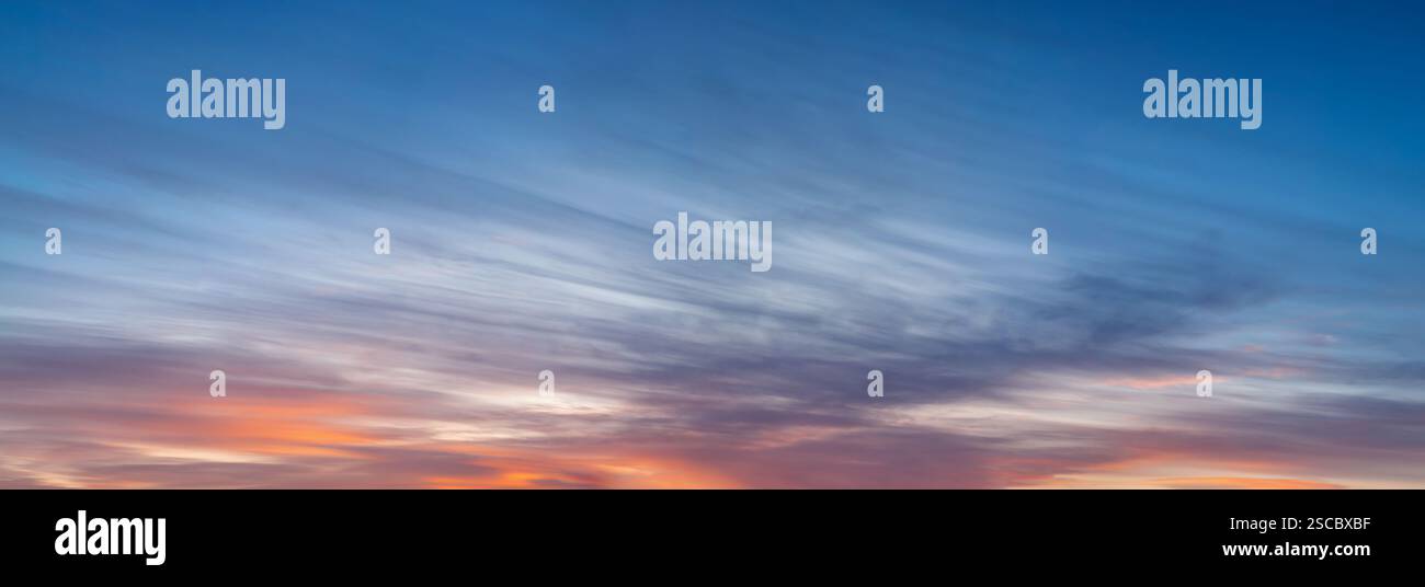 Un grande panorama del cielo prima del tramonto, basse nuvole a strisce di colore rosso brillante. Foto Stock