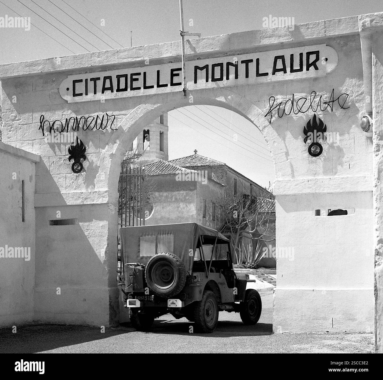 Il cancello d'ingresso di una caserma del legionario straniero in cui un veicolo fuori strada sta guidando attualmente. La jeep è una jeep Willys CJ5. [traduzione automatica] Foto Stock