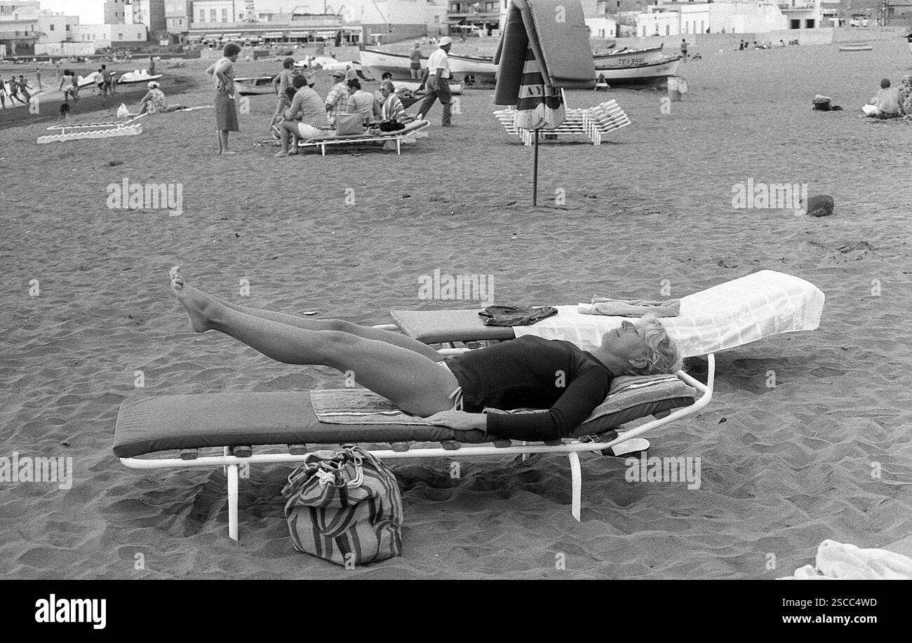 Una donna addestra i suoi muscoli addominali su un divano sulla spiaggia a Los Christianos a Tenerife. [traduzione automatica] Foto Stock