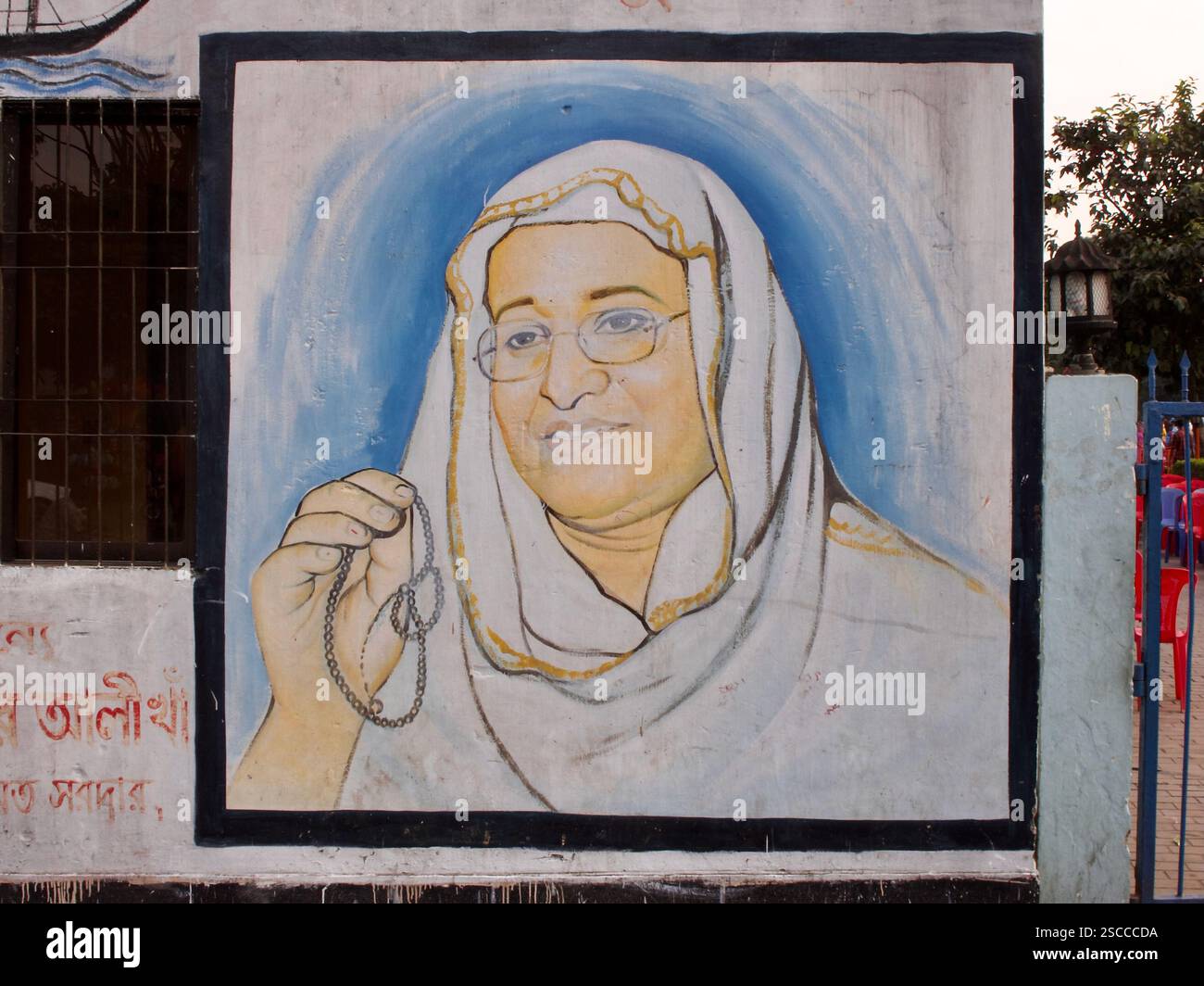 Murale dipinto a mano dello sceicco Hasina a Dacca, raffigurante l'ex leader in una posa religiosa con perline di preghiera, che riflette l'iconografia politica. Foto Stock