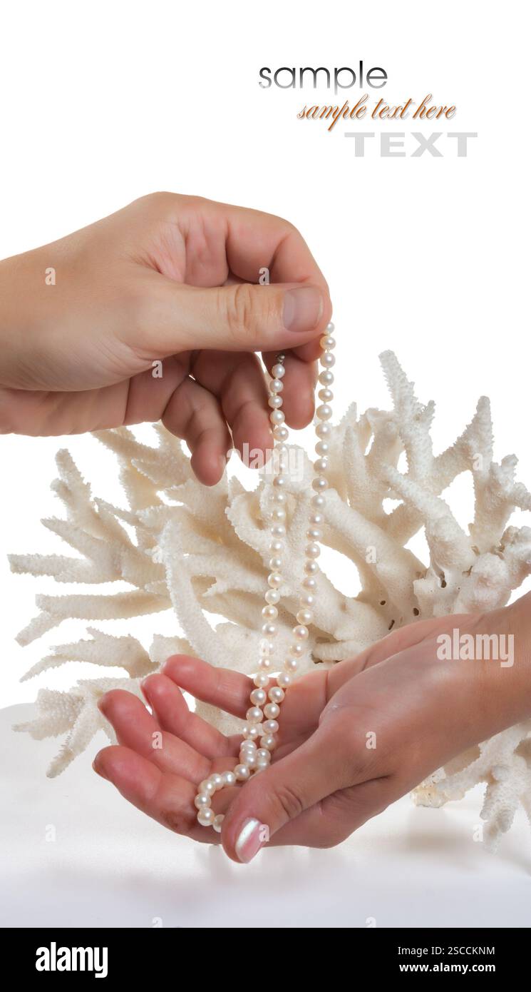 Una collana di perle nelle sue mani contro lo sfondo di corallo isolato su uno sfondo bianco Foto Stock