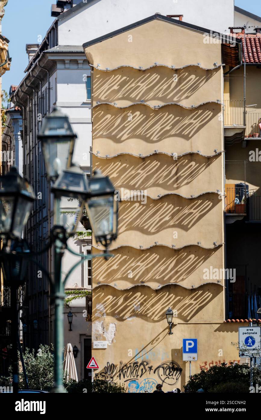 Torino, Italia. Il Palazzo delle Ombre è un'opera d'arte di Nancy Dwyer. Il sole scrive sulla facciata la parola "più" in cinque lingue. Foto Stock