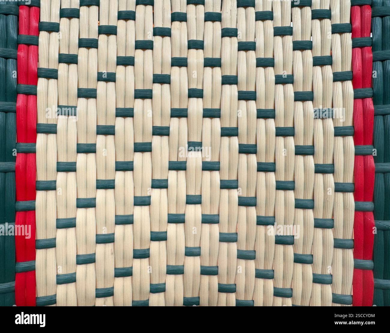 Primo piano della tessitura sintetica in rattan o vimini con motivo a chevron, colori rosso, verde e beige. Sfondo in rattan intrecciato a mano senza cuciture. Foto Stock