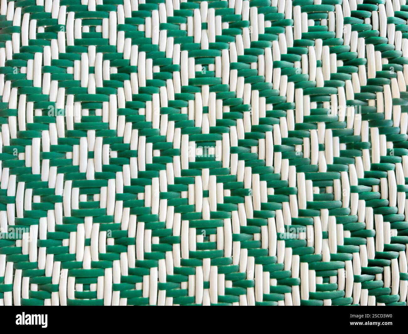 Primo piano di intrecci sintetici di rattan verde e bianco o vimini con motivo a chevron e diamante. Sfondo in rattan intrecciato a mano senza cuciture. Foto Stock