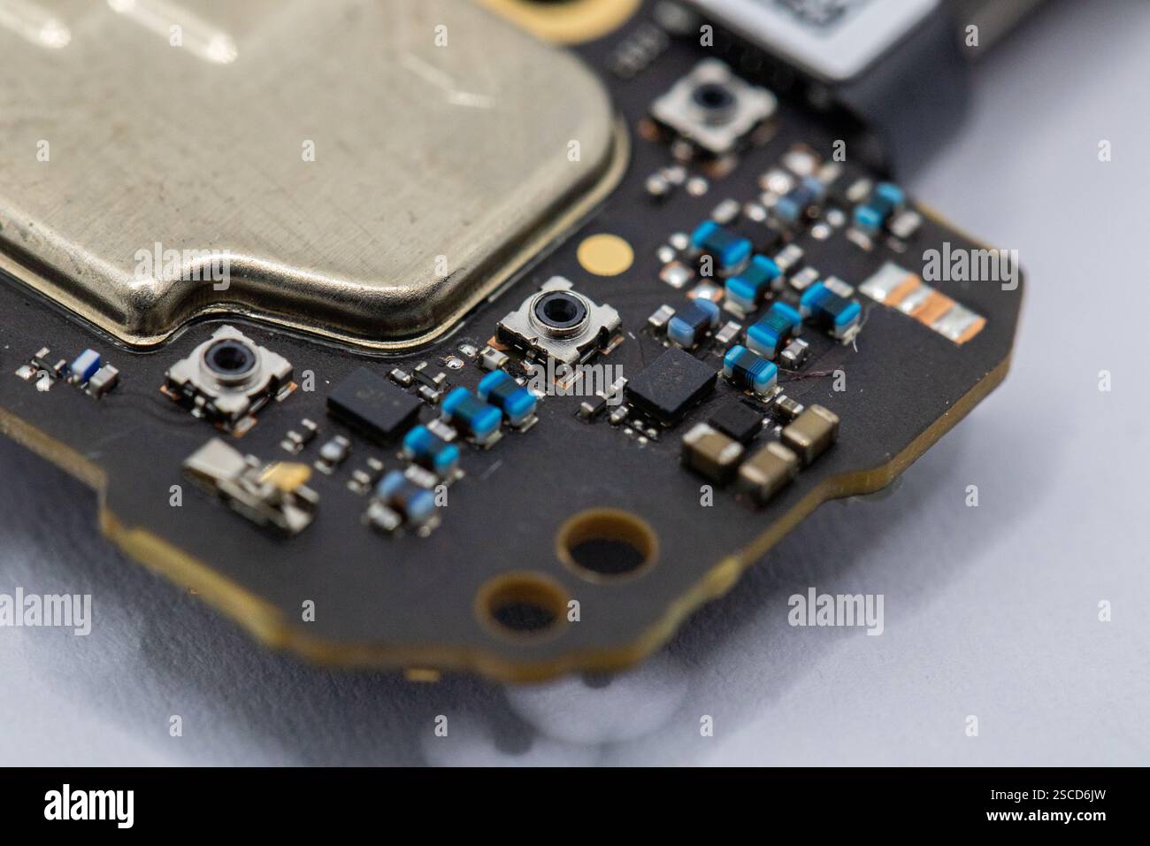 Primo piano di un frammento di circuito stampato, che mostra vari componenti tra cui un elemento metallico, resistenze a montaggio superficiale e piccoli pulsanti. Predomina Foto Stock