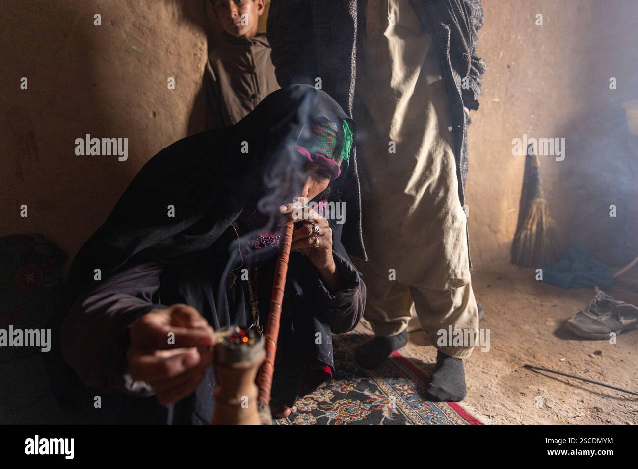 Un'anziana donna afghana prepara un Chilim, un narghilè tradizionale pieno di tabacco naturale. Mentre la maggior parte delle donne afghane rompono narghilè, alcune ancora li usano Foto Stock