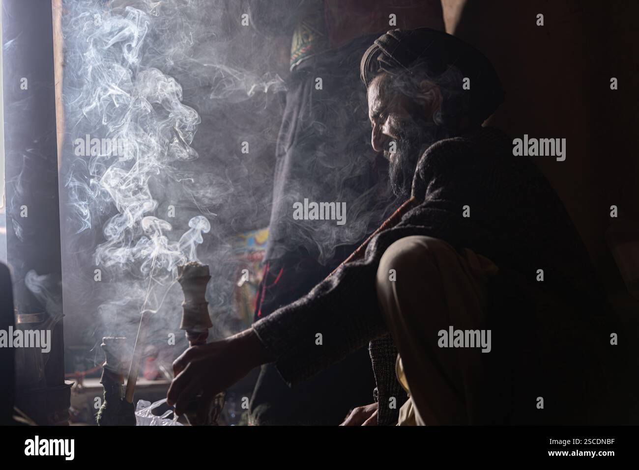 Un uomo afghano sta fumando un chilim (narghilè tradizionale). Foto Stock