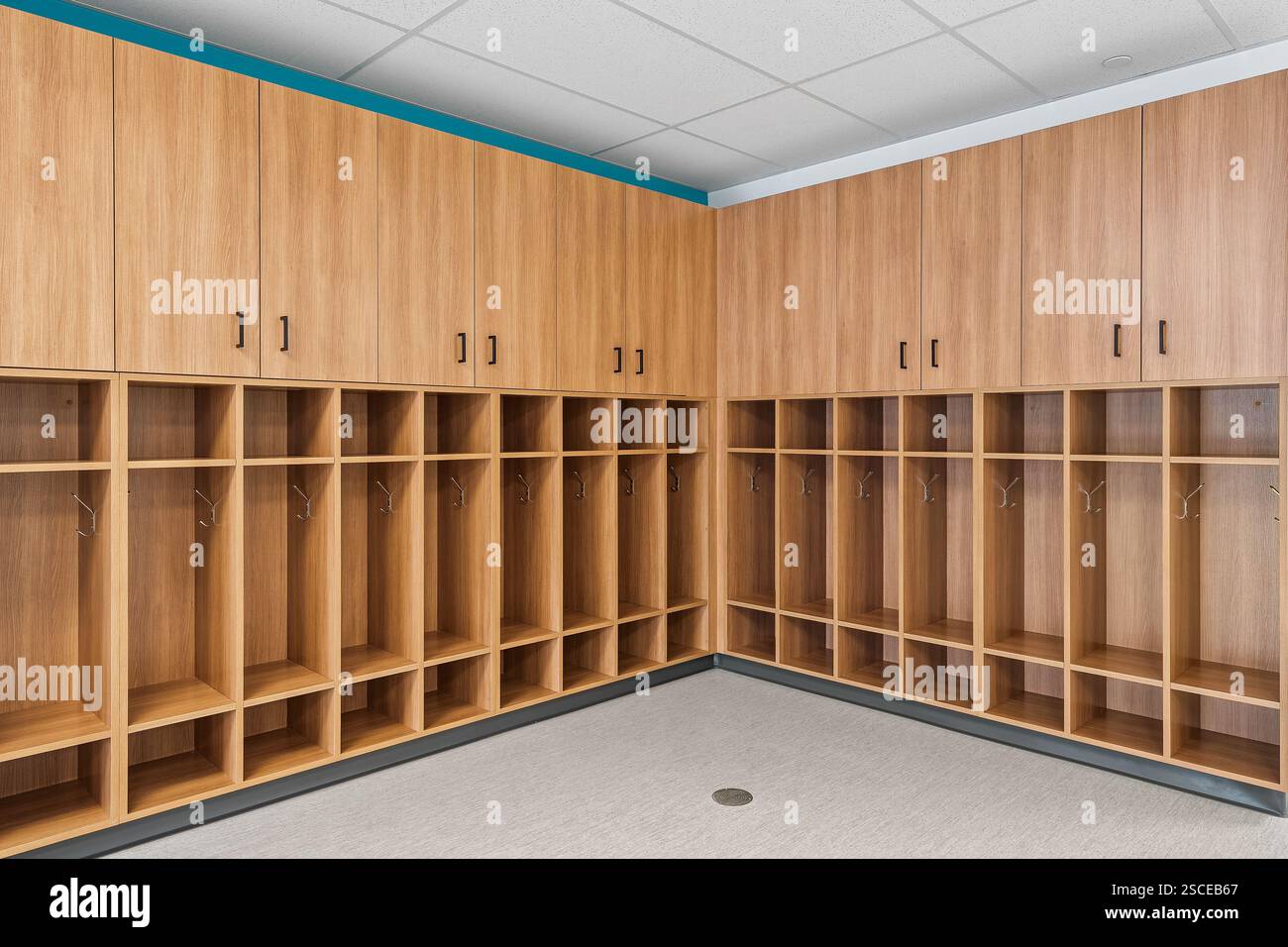 Una grande sala con armadietti in legno e un cestino metallico. La camera è vuota e ha un aspetto molto pulito e organizzato Foto Stock