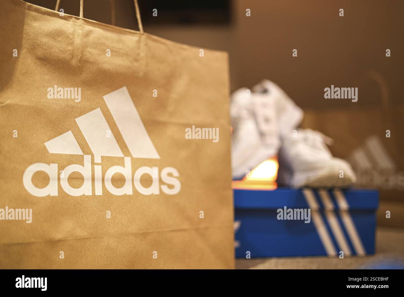 Incentrata sulla shopping bag Adidas con le sneakers su una scatola per scarpe blu nelle vicinanze Foto Stock