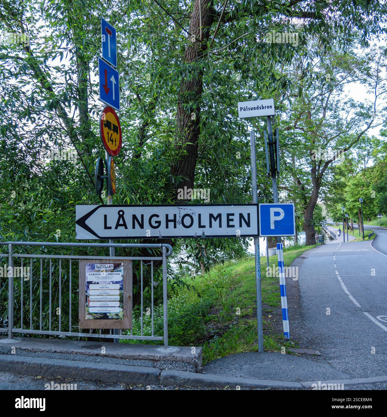 Stoccolma, Svezia - 13 giugno 2024: Un cartello stradale che indica le indicazioni per Långholmen, il nome della piccola isola, e parcheggio, circondato dal verde Foto Stock