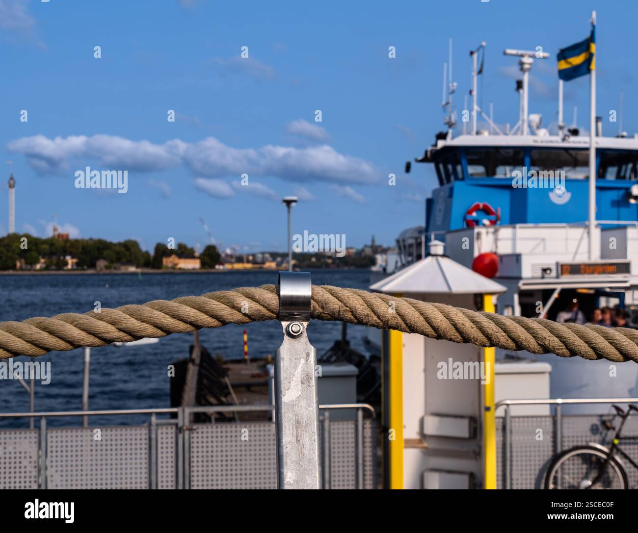 Stoccolma, Svezia - 20 agosto 2024: Un traghetto attraccato in un molo con una barriera di corda in primo piano, sullo sfondo di un mare calmo e di un blu chiaro Foto Stock