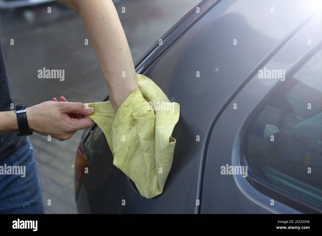 Pulire a mano vicino al tappo del serbatoio dell'auto con un asciugamano alla luce del sole Foto Stock
