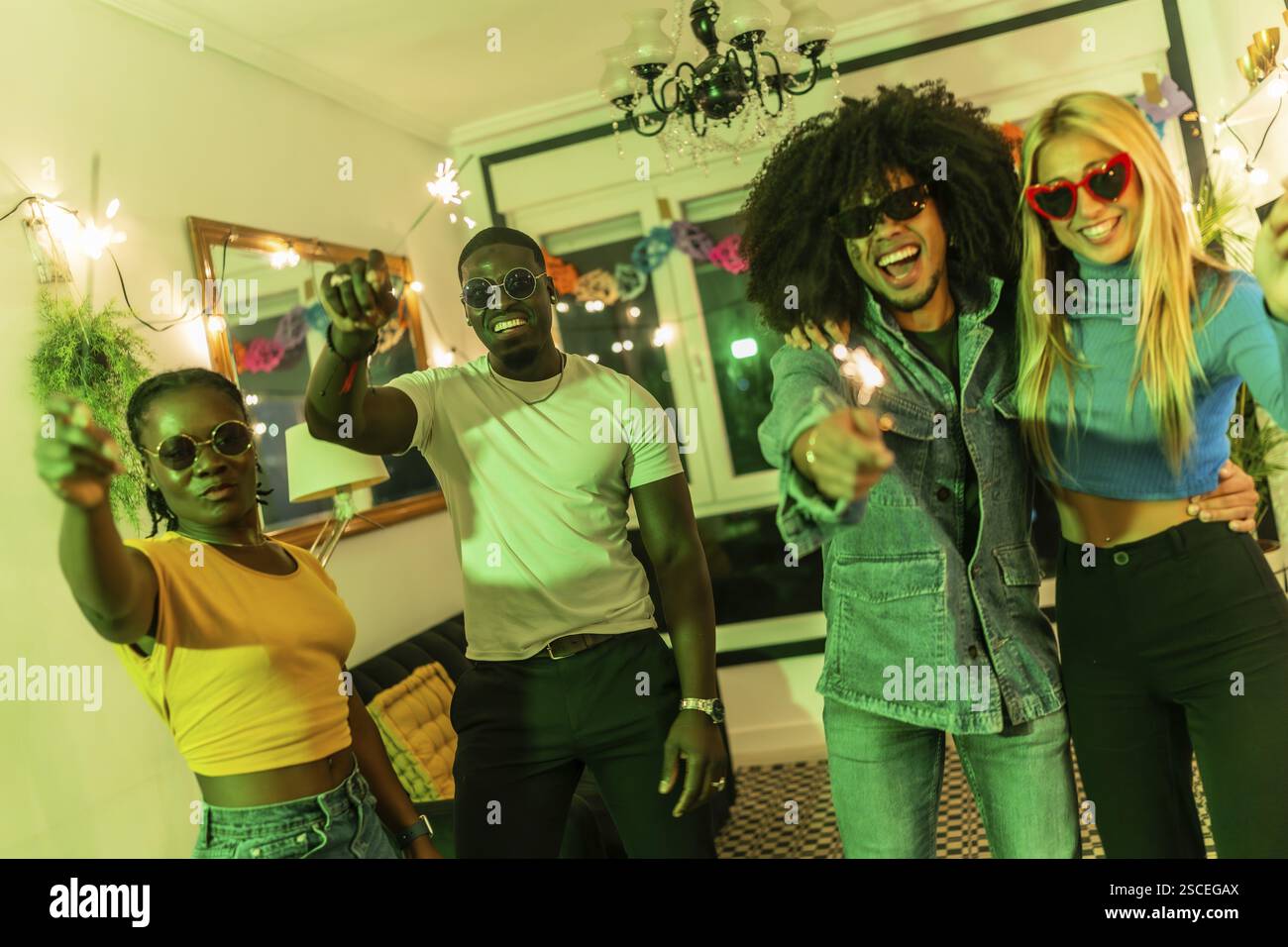 Amici multietnici che scatenano scintille in salotto durante una festa in casa Foto Stock