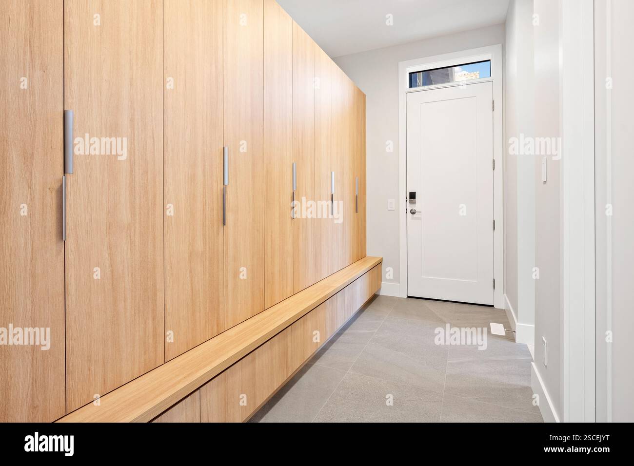 Un corridoio con armadi in legno e una porta bianca. Il corridoio è vuoto e la porta è aperta Foto Stock