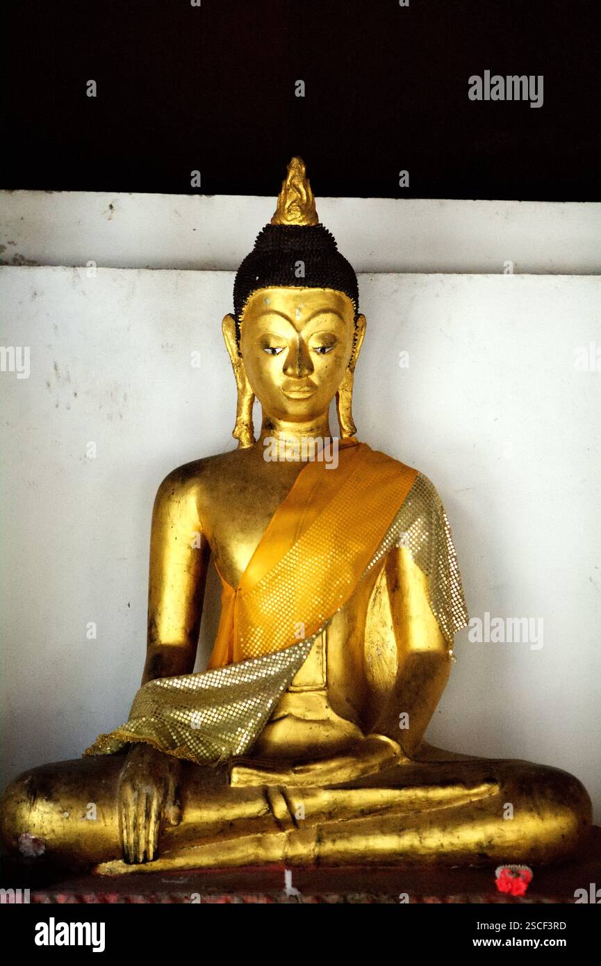 Una scultura dorata di Buddha in un vicolo del tempio Wat Phra Boromthat a Nakhon si Thammarat, Thailandia. Foto Stock