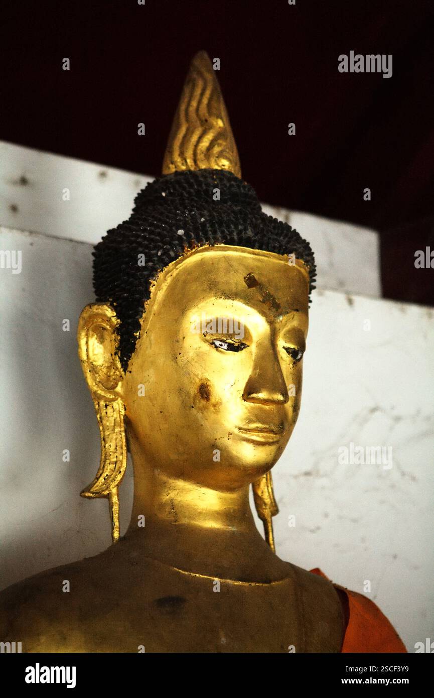Una scultura dorata di Buddha in un vicolo del tempio Wat Phra Boromthat a Nakhon si Thammarat, Thailandia. Foto Stock