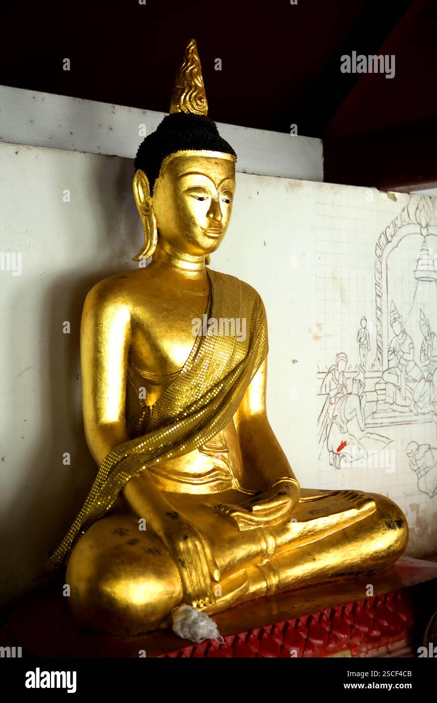 Una scultura dorata di Buddha in un vicolo del tempio Wat Phra Boromthat a Nakhon si Thammarat, Thailandia. Foto Stock