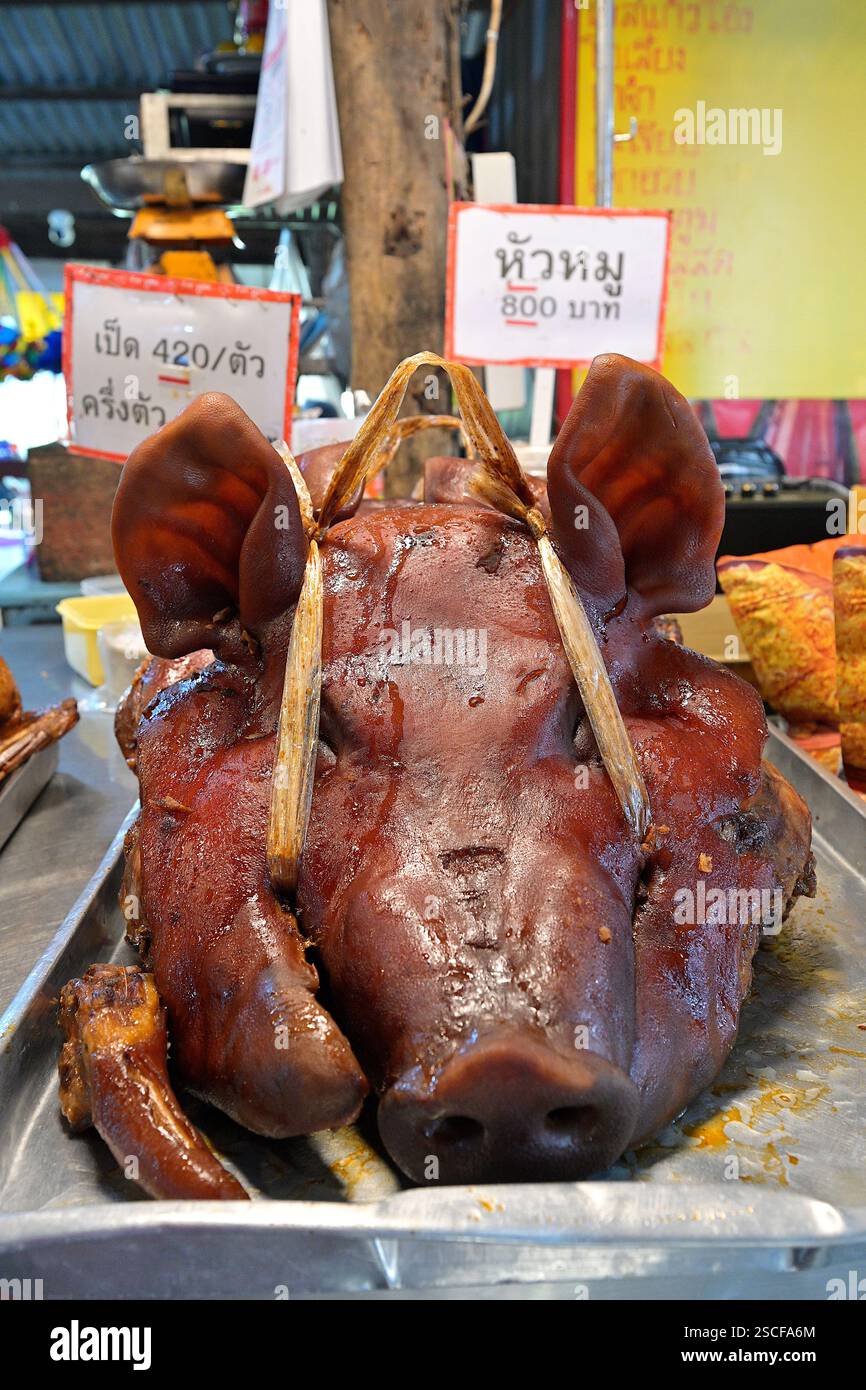 Un'intera testa di maiale brasata, un piatto cinese fatto con ingredienti sospesi in uno stufato a base di salsa di soia, visto qui in una bancarella del mercato in Thailandia Foto Stock