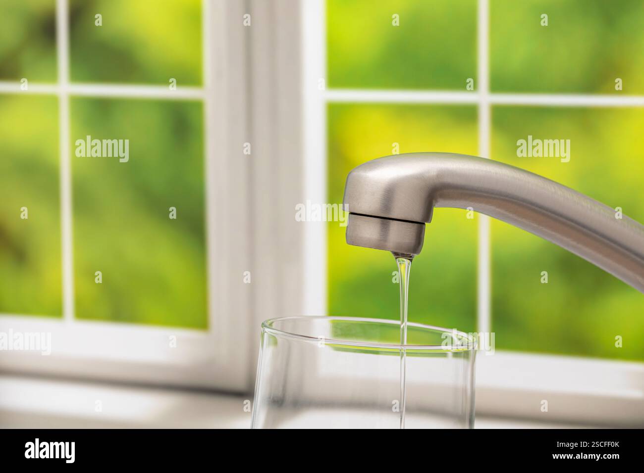 Pressione dell'acqua bassa dal rubinetto della cucina. Concetto di conservazione dell'acqua, carenza e acqua potabile sicura. Foto Stock