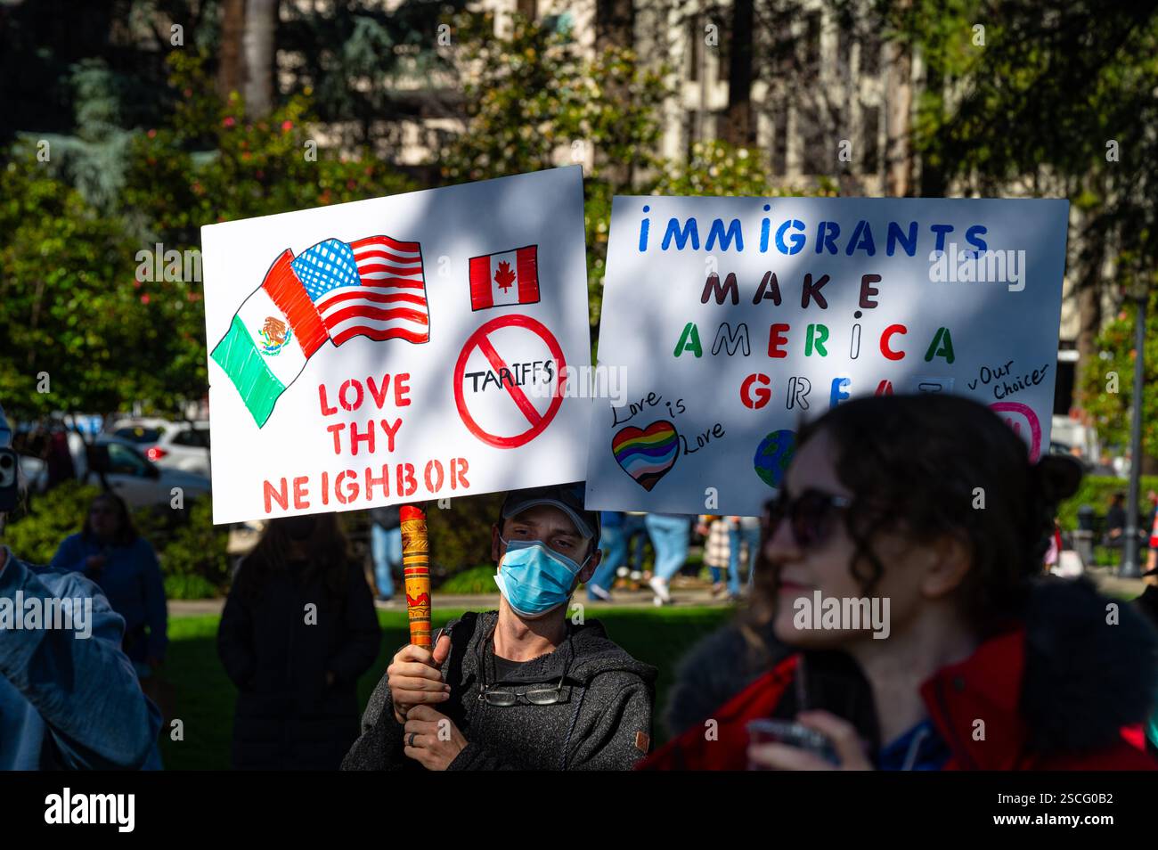 Un manifestante alla marcia anti-Trump del 50501 ha un segnale sulle tariffe contro Canada e Messico e uno sugli immigrati. Foto Stock