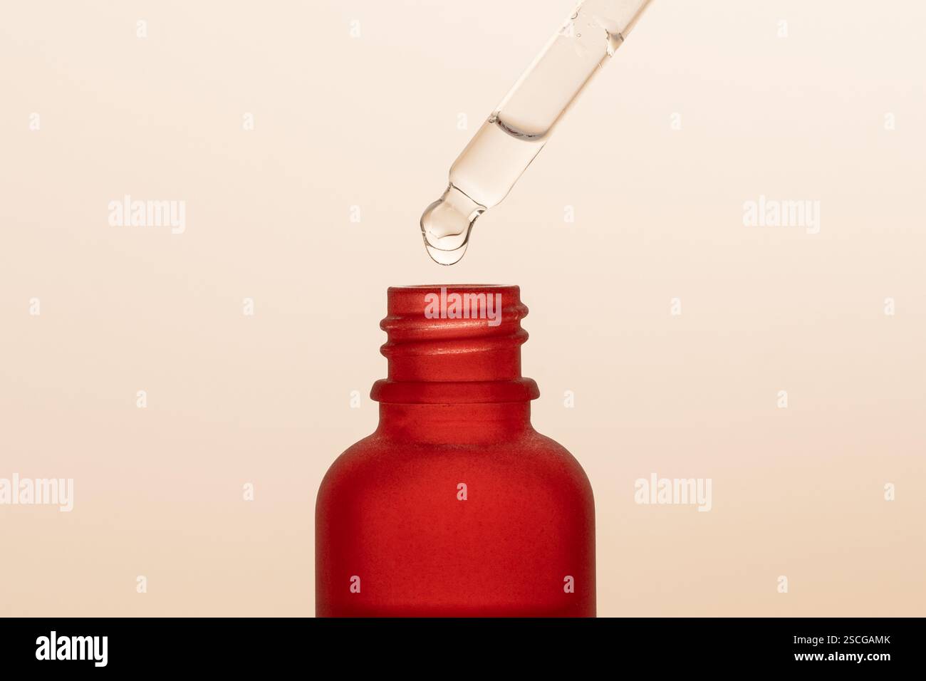 Una goccia sull'estremità della pipetta del siero con contagocce rosso. Presentazione del prodotto. Linea di marketing Foto Stock