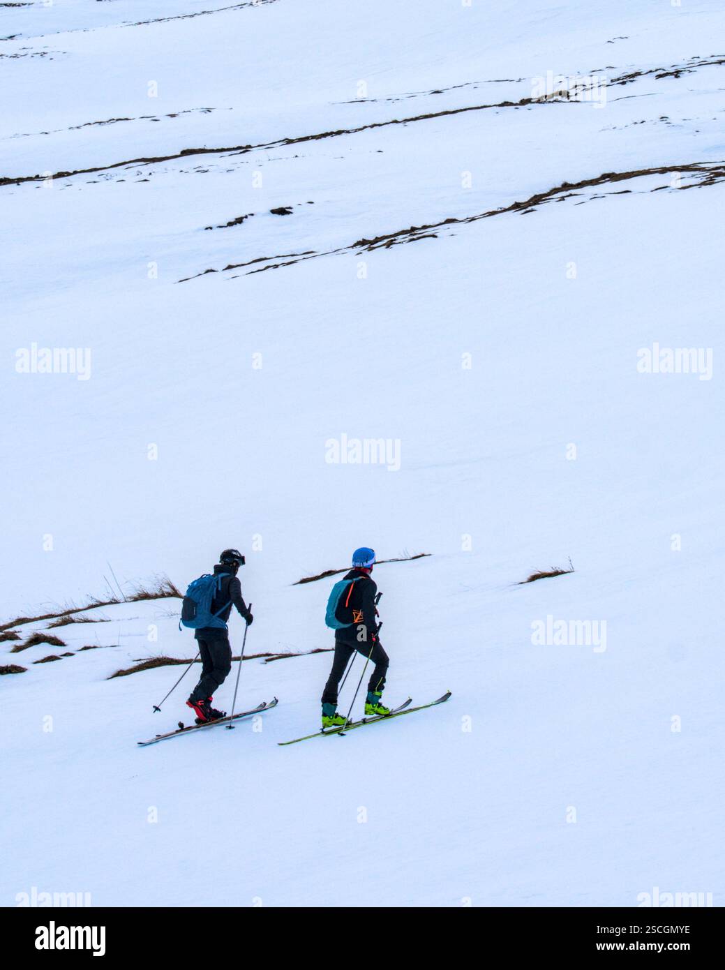 Sci alpino su una montagna coperta di neve da due persone che si muovono in salita Foto Stock