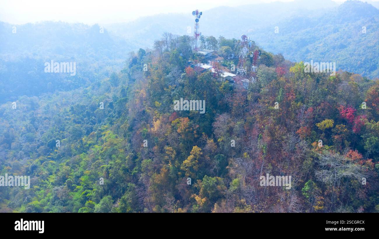 Vista aerea dell'antenna cellulare o della torre di comunicazione su un bellissimo paesaggio montano con una foresta colorata in autunno. Foto Stock