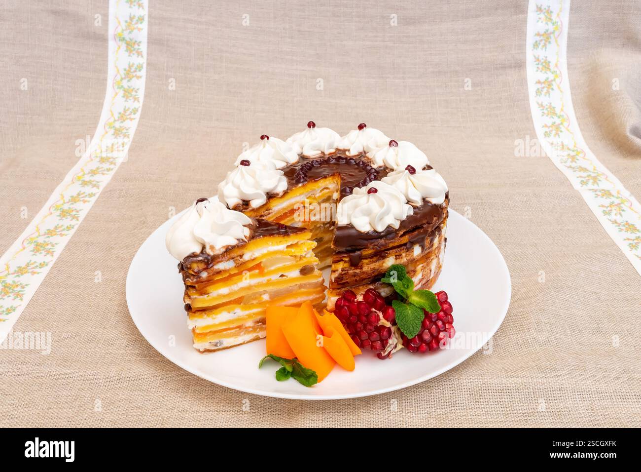 Una torta a strati splendidamente presentata si stende su un piatto bianco. La torta presenta più strati di panna e cioccolato, ricoperti di c Foto Stock