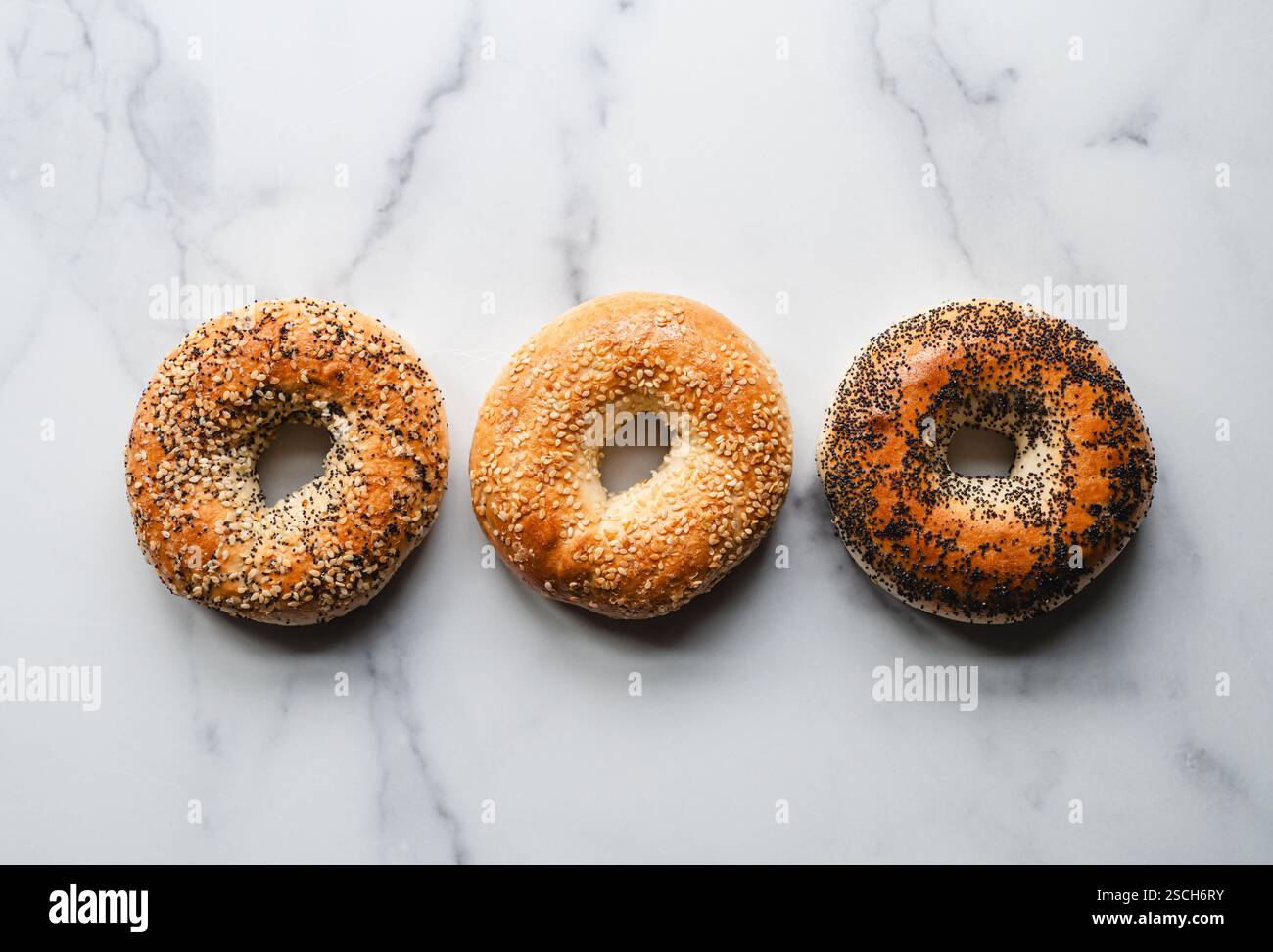 Linea di tre bagel assortiti su sfondo chiaro dall'alto. Foto Stock