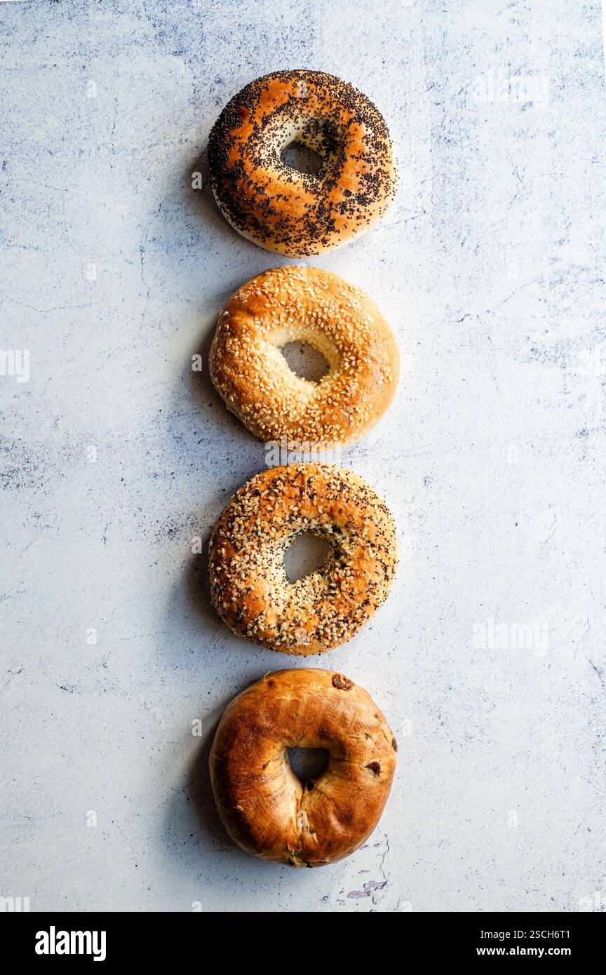 Linea di quattro bagel assortiti su sfondo chiaro dall'alto. Foto Stock