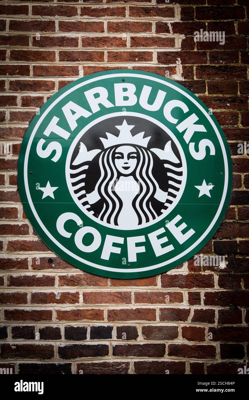 Un cartello con la caffetteria Starbucks su un muro di mattoni. Foto Stock